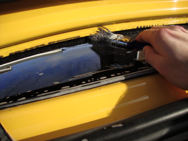 Using a 1" 25mm brush, and car shampoo mixed with water, you can remove a lot of dirt trapped between the glass and rear metal surround of the boot.